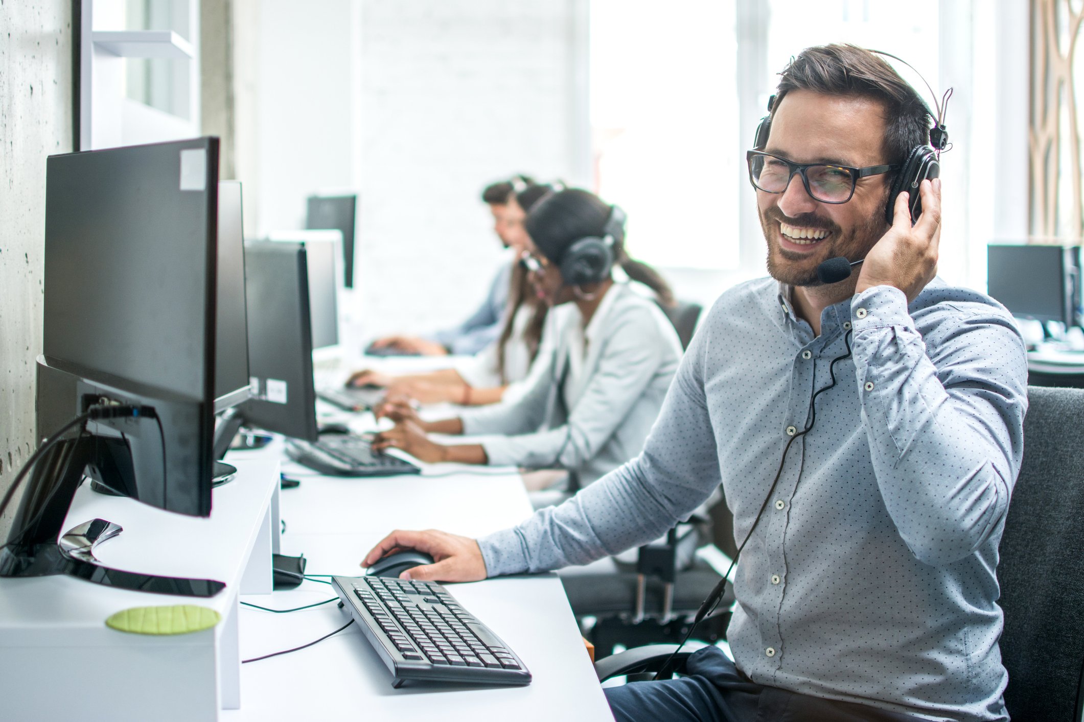 Employee working on computer smiling with earphones